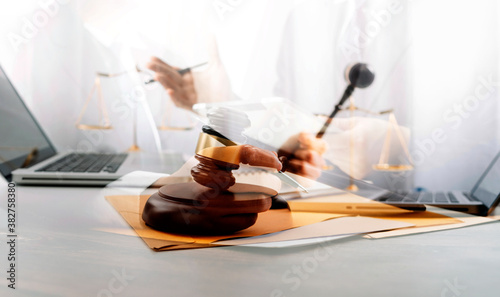 Justice and law concept.Male judge in a courtroom with the gavel, working with, computer and docking keyboard, eyeglasses, on table in morning light