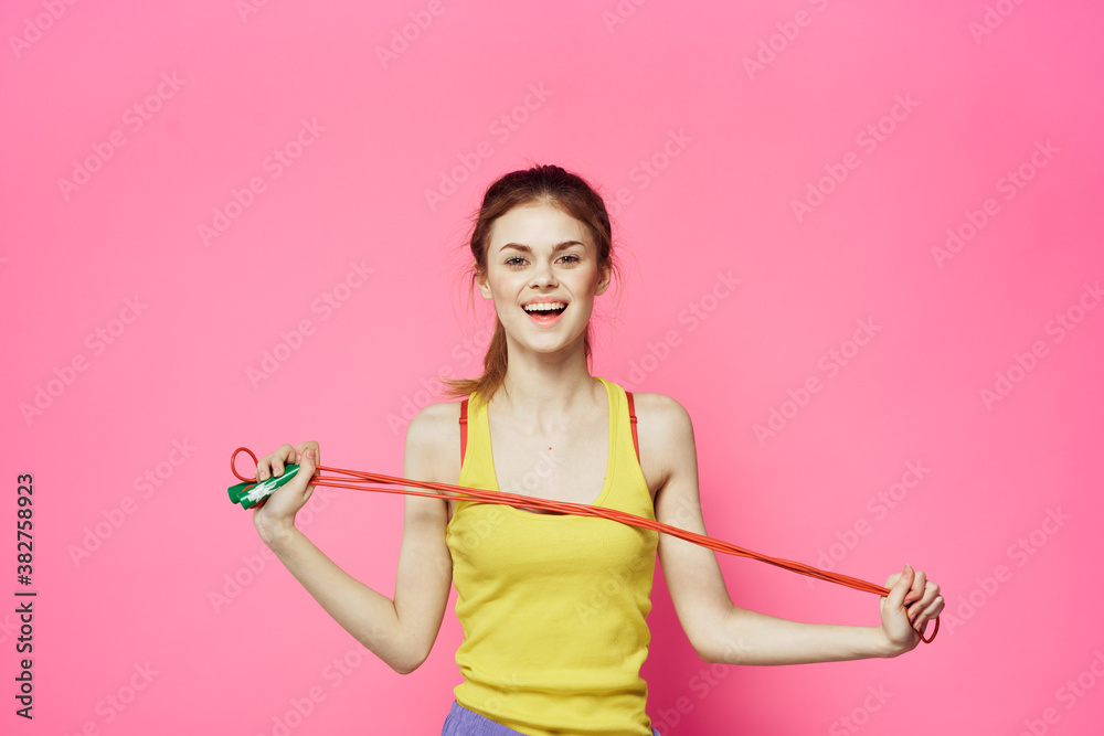 Sportive woman jumping rope friend exercise yellow tank top workout pink background Sportive woman jumping rope friend exercise yellow tank top workout pink background