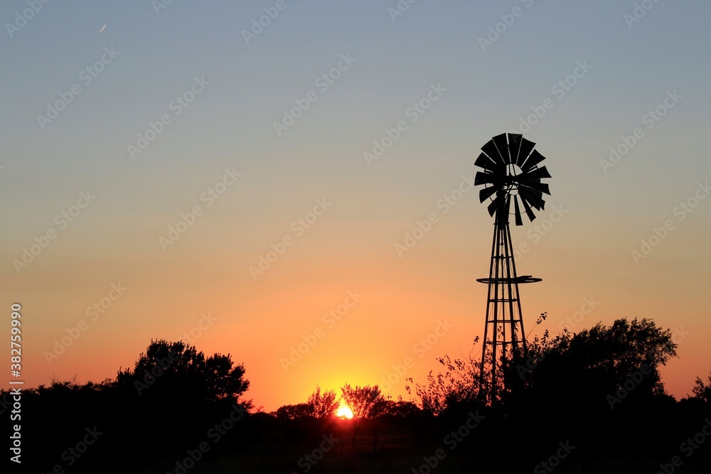 windmill at sunset with silhouette out in the country north of Hutchinson Kansas USA. windmill at sunset with silhouette out in the country north of Hutchinson Kansas USA.
