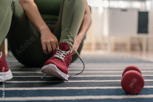 A woman is wearing shoes to exercise in her home. Exercise indoors during quarantine. Exercise  home activities