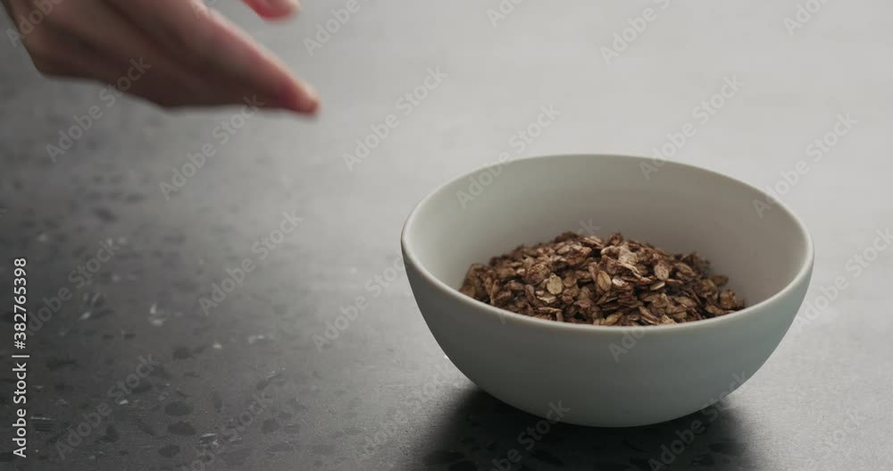 Slow motion man hand place white bowl with chocolate granola, strawberries and glass for yogurt on a concrete countertop Slow motion man hand place white bowl with chocolate granola, strawberries and glass for yogurt on a concrete countertop