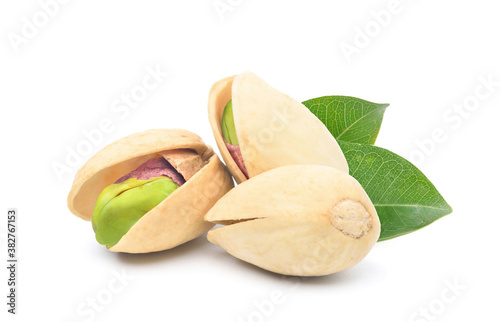Pistachio nuts with green leaves isolated on white background.