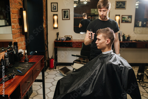 Sensual manly professional hairdresser looking client's hair length