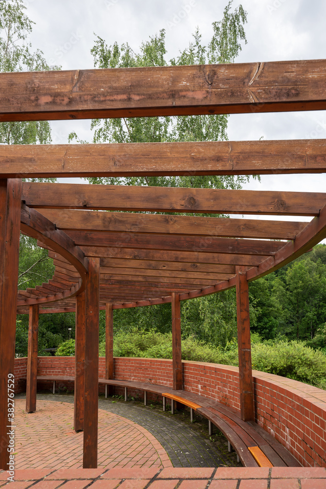 New round wooden pergola with long bench in the park