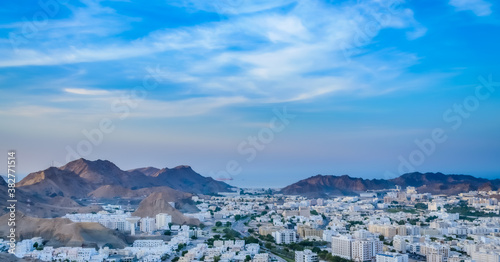 Wide View of Muscat Cityscape with blue sky and mountains from the top of a hill. From Oman. © rejittiachan