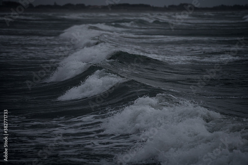 Fototapeta Naklejka Na Ścianę i Meble -  Intentionally dark image of rough seas with waves crushing on the beach during high tide and scirocco - Venice, Italy 
