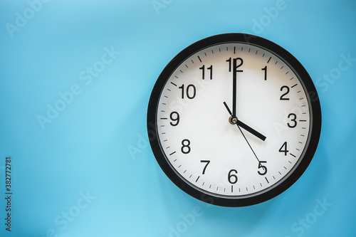 Classic black and white analog clock on blue background at Four o'clock with copy space