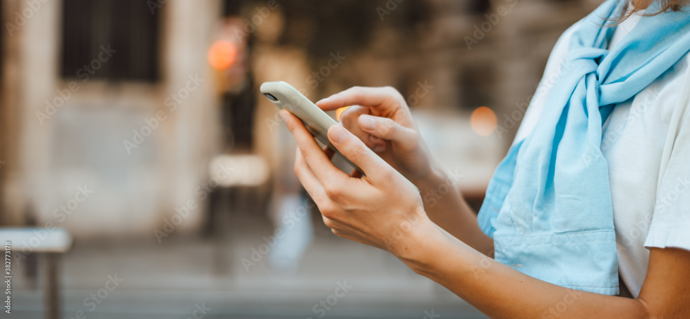Close-up photo of female hands with smartphone. Young woman typing on a mobile phone on a street Close-up photo of female hands with smartphone. Young woman typing on a mobile phone on a street