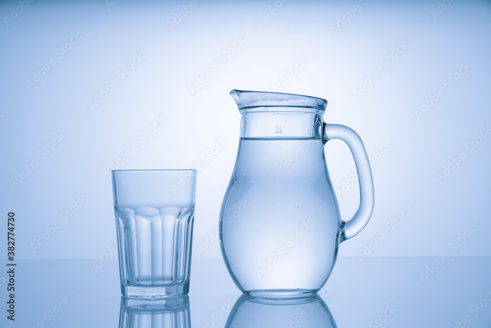 Pitcher with drinking water and a glass with a drink, blue tone Pitcher with drinking water and a glass with a drink, blue tone