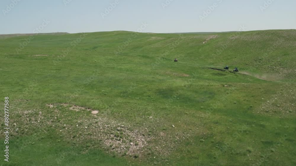 Aerial, tracking, people on ATVs in an empty green landscape, WY, USA Aerial, tracking, people on ATVs in an empty green landscape, WY, USA