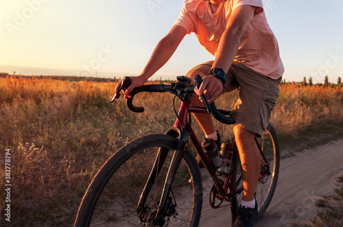 Cyclist riding in a field at sunset. Man on bicycle at sunset close up. Active lifestyle concept.