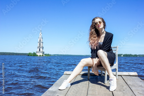 A girl in a black jacket against the background of the Uglich reservoir Kalyazin city. Rocky shore.