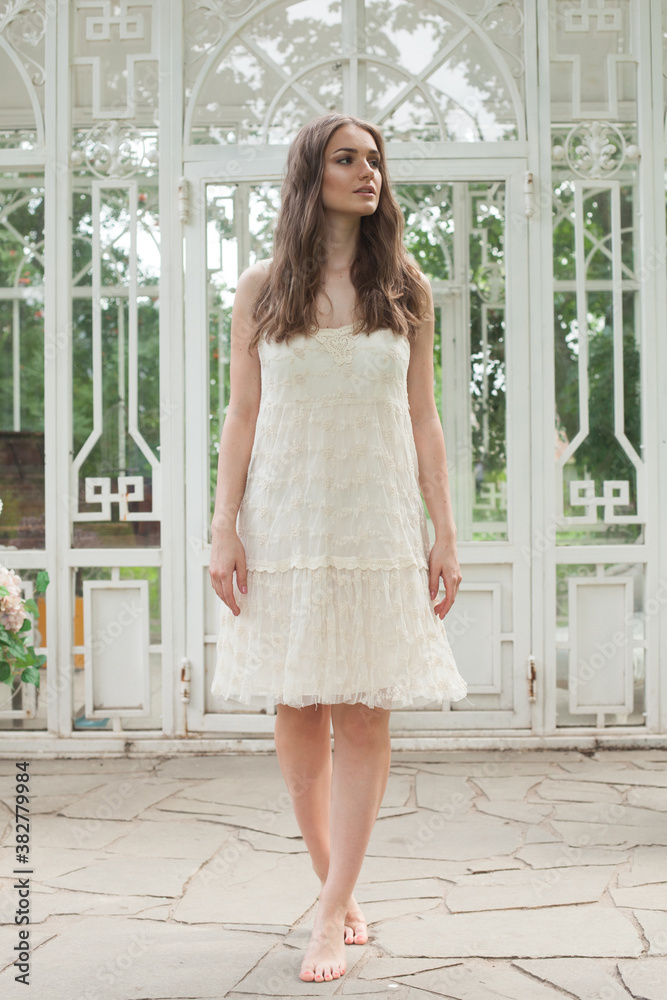 Obraz premium Nice young woman wearing white dress standing in the yard