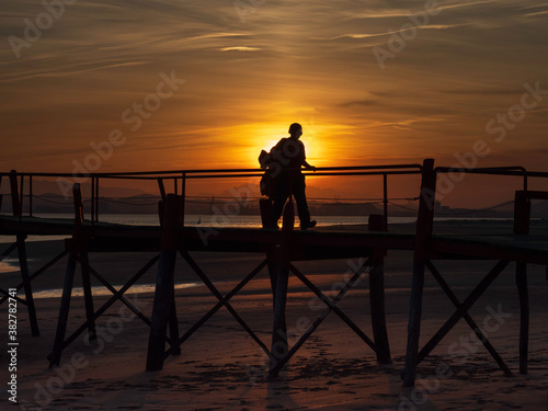 young man silhouette at sunset on the old pier