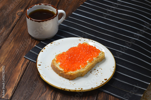 Cup of coffee and sandwich bread with butter and red salmon caviar top view, healthy breakfast
