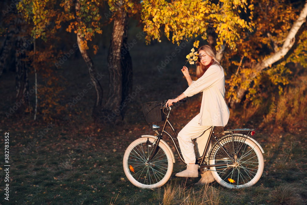 Fototapeta premium Happy active young woman riding bicycle in autumn park