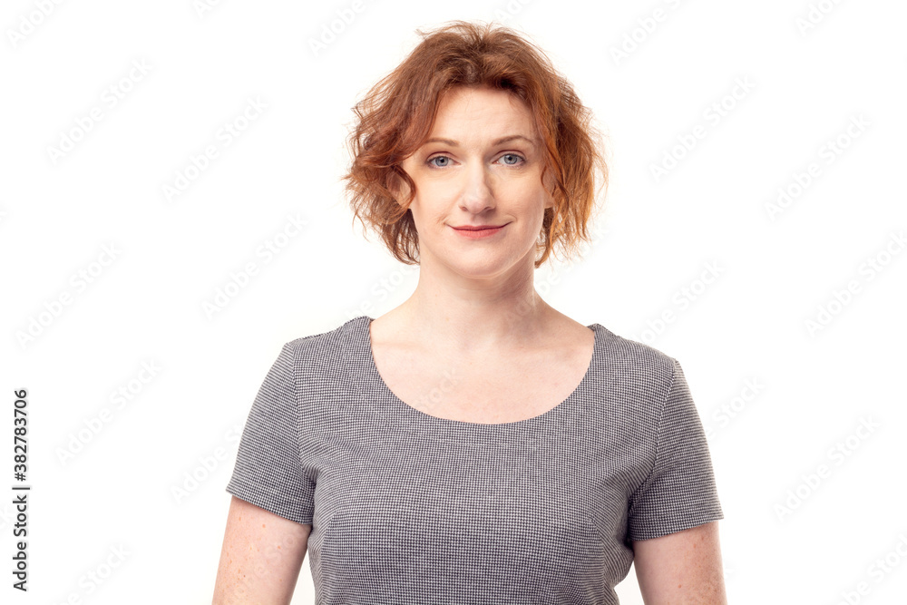 Beautiful red haired adult mature woman in gray dress looking into camera Beautiful red haired adult mature woman in gray dress looking into camera