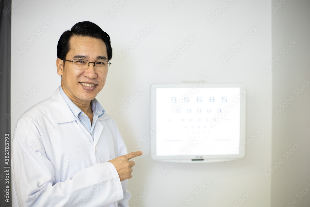 An Asian man Optometrists point to vision charts to examine the eyesight of patients in an ophthalmology clinic. He has a smiling face An Asian man Optometrists point to vision charts to examine the eyesight of patients in an ophthalmology clinic. He has a smiling face