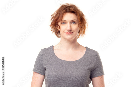 Beautiful red haired adult mature woman in gray dress looking into camera