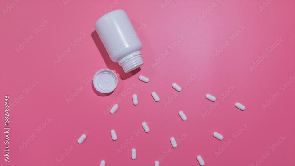 A bottle with white pills gets empty. Pill usage on a pink plain background. Stop Motion A bottle with white pills gets empty. Pill usage on a pink plain background. Stop Motion