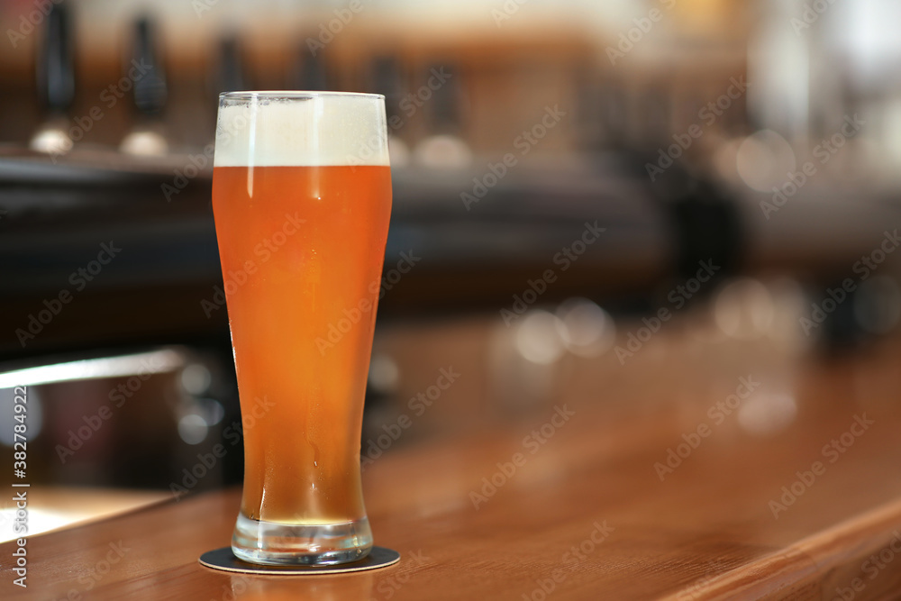 Glass of cold tasty beer on bar counter, space for text Glass of cold tasty beer on bar counter, space for text