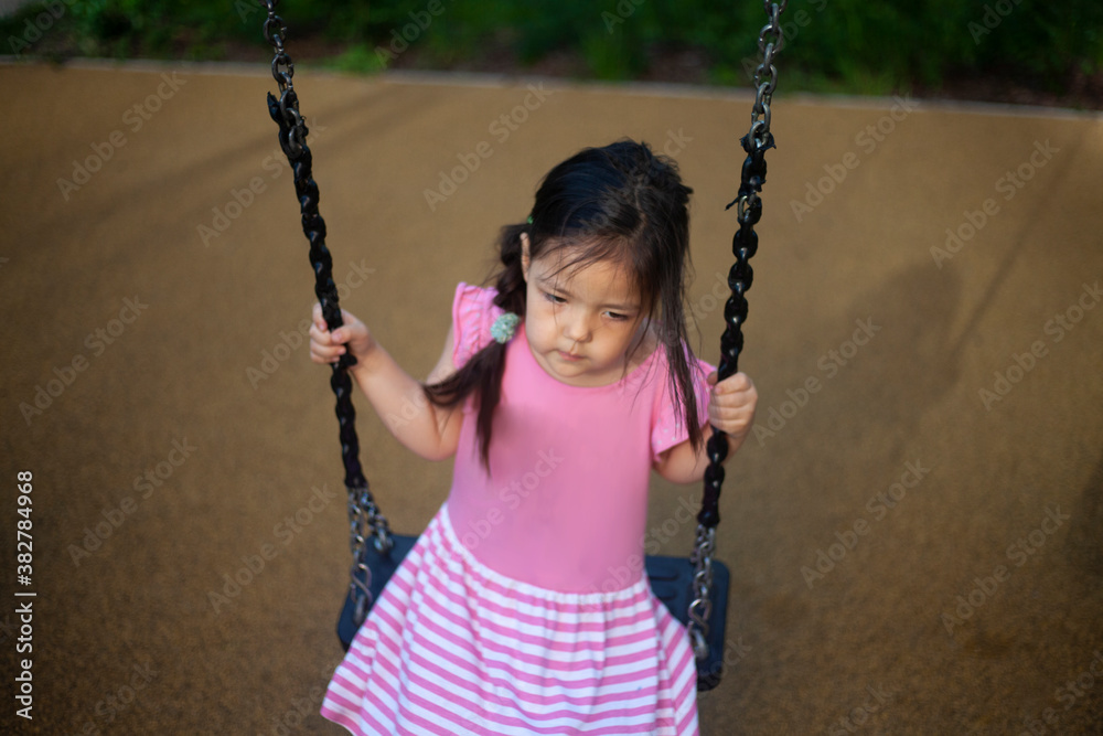 The girl is swinging on a swing. Play on the playground.