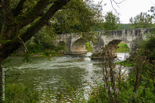 Blick auf die Historische Steinbrücke über die Altmühl bei Pfünz vom Ufer aus zwischen den Bäumen