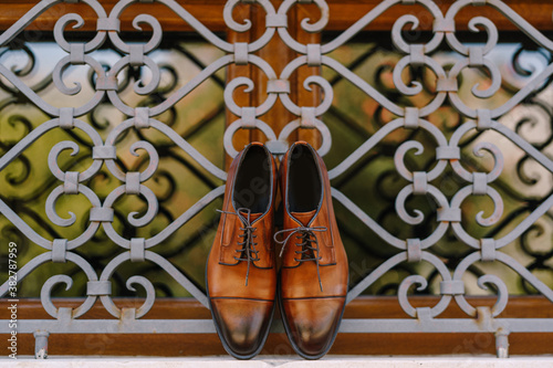 Stylish brown men's shoes made of genuine leather by the window with a metal lattice.