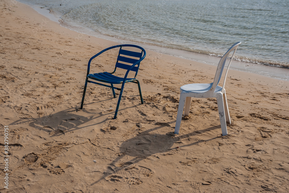Chairs on the sandy seashore with shadows