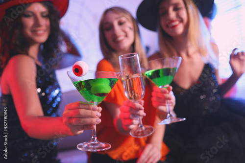 Group of friends toasting with cocktails at Halloween party indoors
