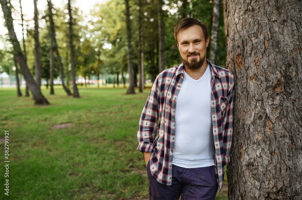 Bearded man standing near the tree in summer park Bearded man standing near the tree in summer park