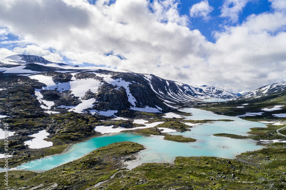 Scenic Gamle Styrnefjellsvegen with turquoise lake and snowcapped Mountains, Grotli, Norway
