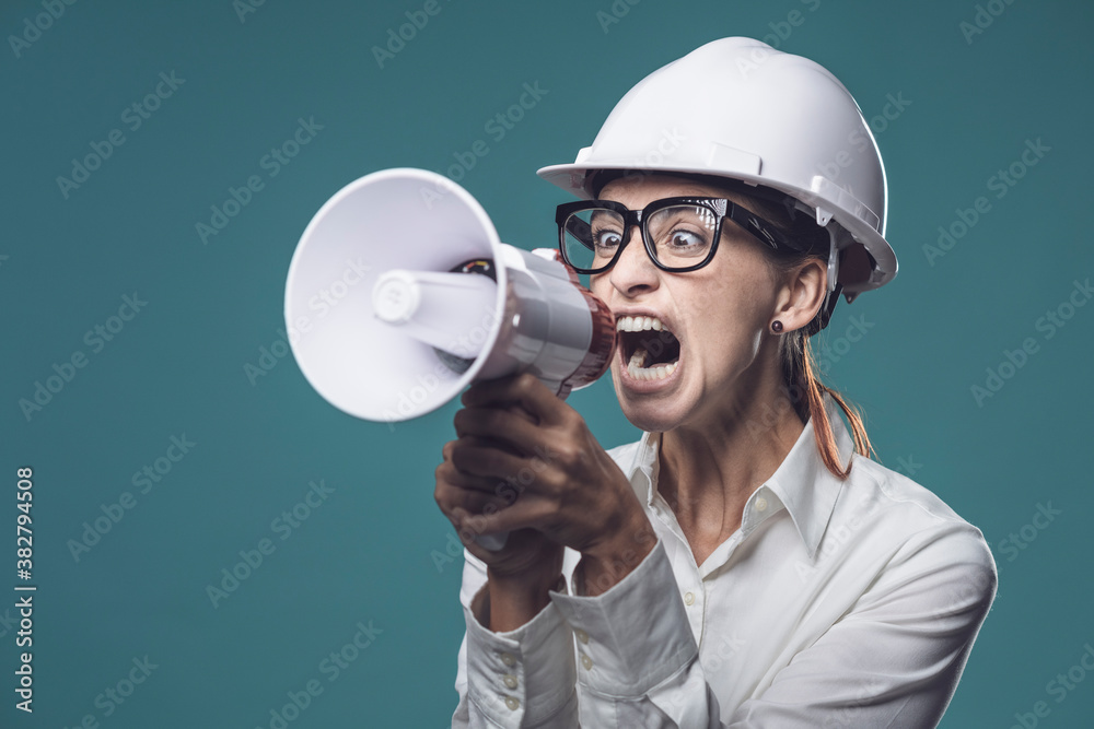 Aggressive businesswoman shouting through a megaphone Aggressive businesswoman shouting through a megaphone