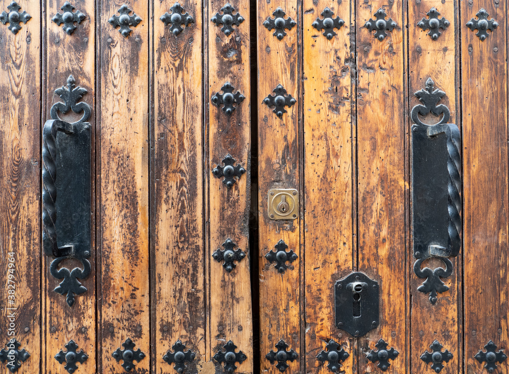 Details of ancient wooden door with iron decorations.Light wood worn by time Details of ancient wooden door with iron decorations.Light wood worn by time