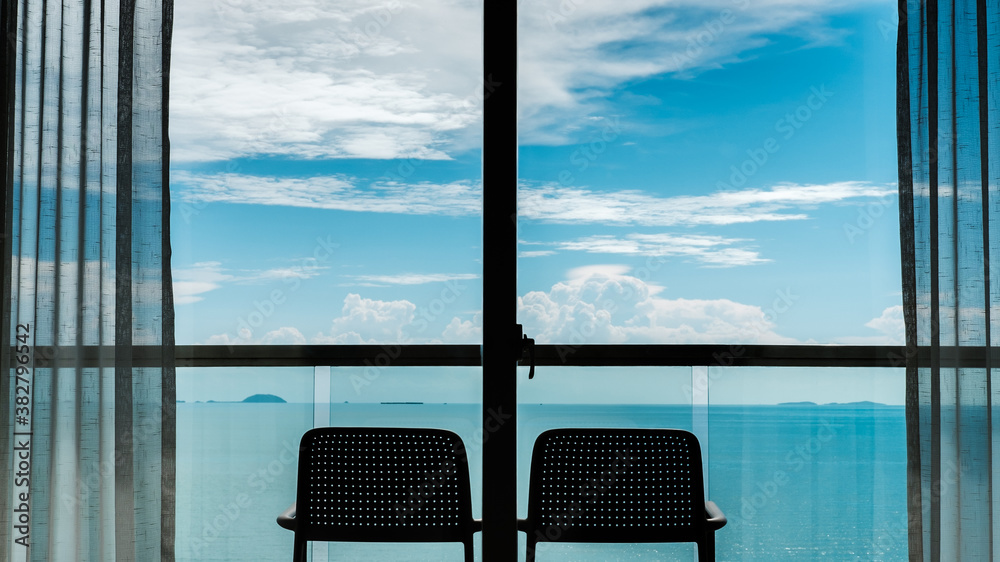 Fototapeta premium Back view from the window of 2 chairs on the balcony, sea and sky views.