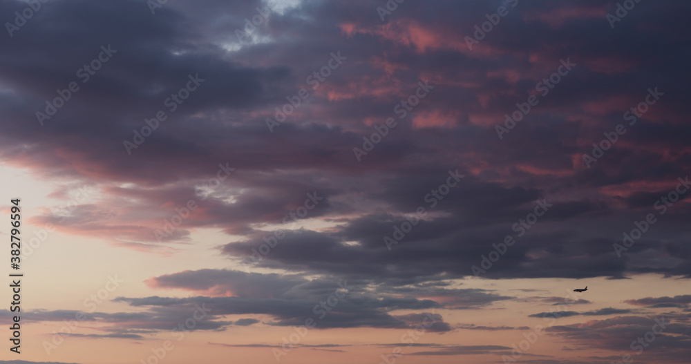 background of clouds on evening sky with bird and landing plane
