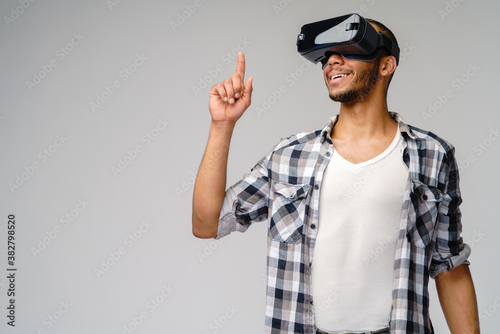 Young African-American young man wearing vr virtual reality headset over light grey background Young African-American young man wearing vr virtual reality headset over light grey background