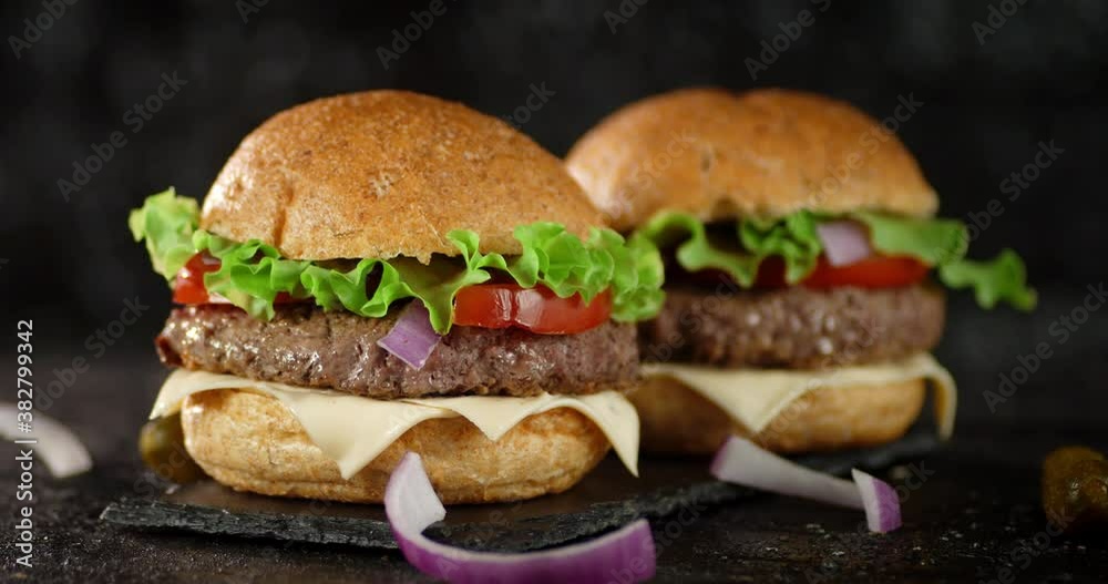 Two delicious burgers on a stone board rotate. Two delicious burgers on a stone board rotate.