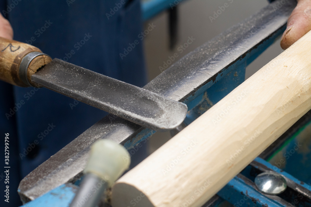 hands hold a chisel for processing on the turning machine of a wooden bar hands hold a chisel for processing on the turning machine of a wooden bar