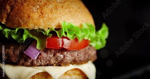 A delicious burger with beef patty rotates on the table. 