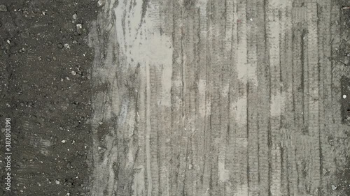 Drone aerial view of mud wild road with track path of vehicle in cloudy day. Drone moving along the dirt road with textures. Epic dark wild cityscape footage. Sand and mud road in Shanghai China