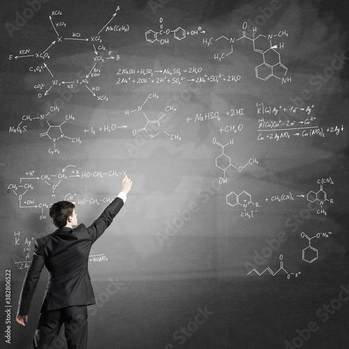 Scientist writing formulas on chalkboard