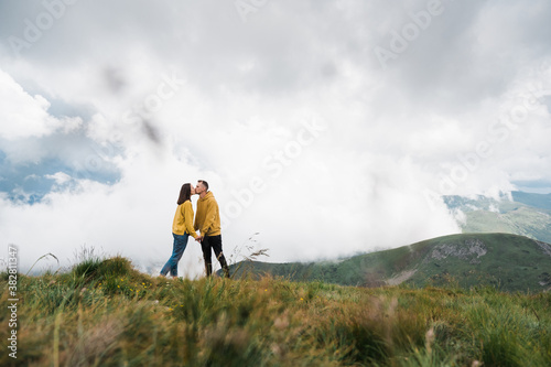 A loving couple kissing holding hands and standing on the top of the mountain against the background of a beautiful landscape