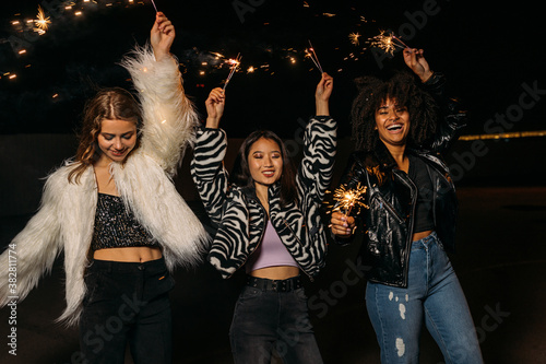 Multiethnic group of young female friends having fun holding sparklers