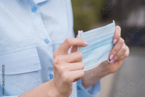 Close-up female hands holding a medical protective mask