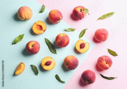 Fototapeta Naklejka Na Ścianę i Meble -  Fresh ripe peaches and green leaves on color background, flat lay