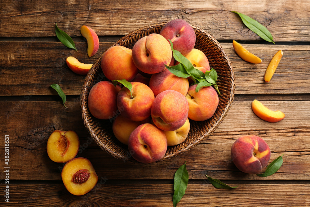 Fresh sweet peaches in wicker basket on wooden table, flat lay Fresh sweet peaches in wicker basket on wooden table, flat lay