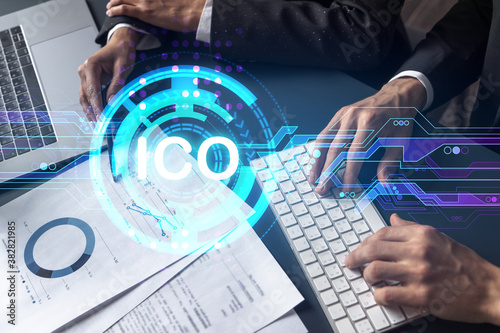 Two business people working together on white paper to release ICO project on market. Try to analyze statistics and optimize transactions processing. Initial coin offer hologram. Double exposure.