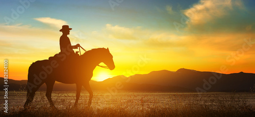 Fototapeta Naklejka Na Ścianę i Meble -  Cowboy on a horse at sunset