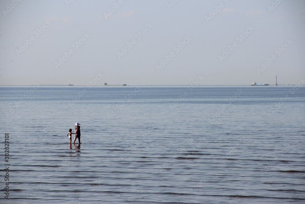 People walking standing and bathing at the beach